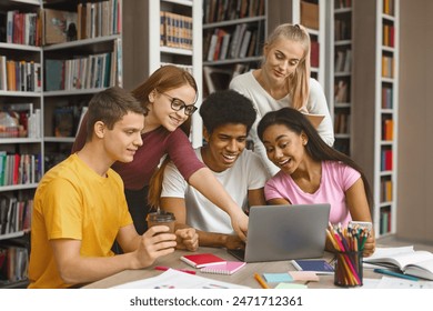 Multinational Team Of College Students Talking Over Project, girl pointing at laptop screen, library interior - Powered by Shutterstock