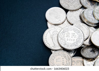 Multiple 1/2, 1, 2, 5 swiss coins franc, centimes CHF money isolated on dark background.