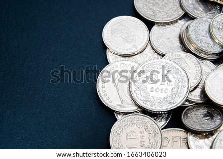 Multiple 1/2, 1, 2, 5 swiss coins franc, centimes CHF money isolated on dark background.