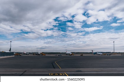 Multiple airplanes with several support and utility vehicles on an airport runway
