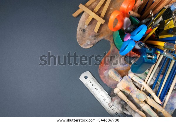 Multiple art tools and classic wooden dummy\
on a gray background.