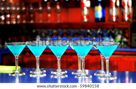 Multiple blue martinis lined up across the bar
