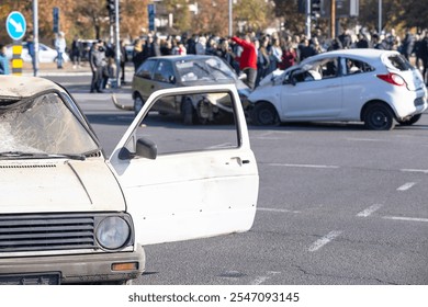 Multiple car collision at busy intersection with crowd gathering at the scene