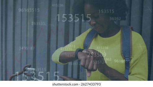 Multiple changing numbers floating over african american woman using smartwatch on the street. Technology concept