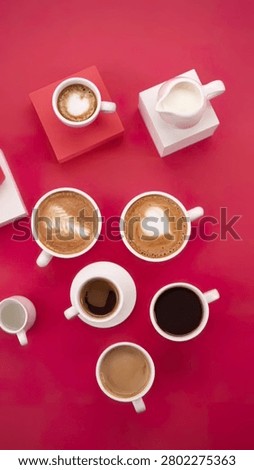 Multiple coffee cups with different drinks and toppings on red surface