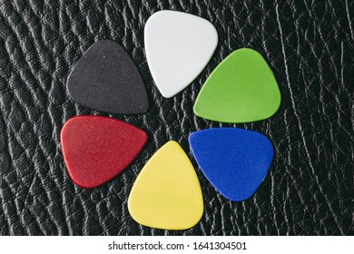 Multiple colored guitar picks placed on a black guitar amp.