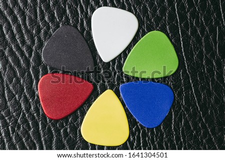 Multiple colored guitar picks placed on a black guitar amp.