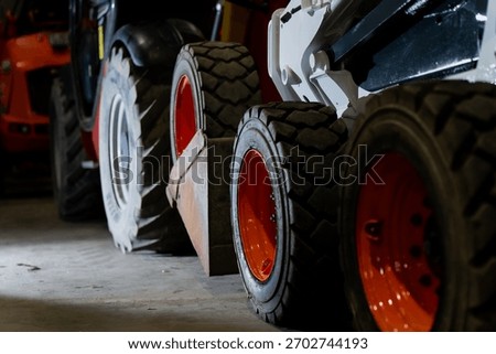 Multiple construction vehicles positioned in storage area featuring robust wheel assemblies, thick tread tires and durable rim structures used for demanding worksite traction and maneuvering tasks