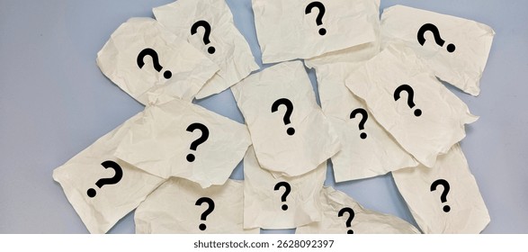 Multiple Crumpled White Paper Sheets with Hand-Drawn Question Marks Scattered on Table – Concept of Confusion, Uncertainty, and Overwhelming Questions. 