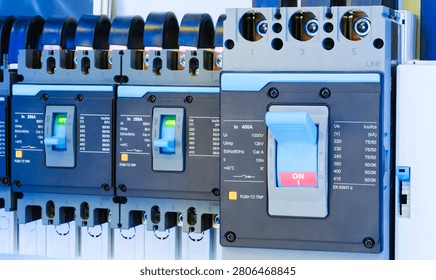 Multiple electrical breakers line a panel. Blue and gray components feature ON OFF labels. White switches indicate operational status clearly. Industrial setting includes wiring and technical markings
