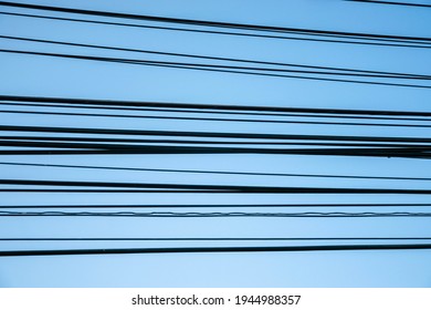 Multiple electrical cables aligned horizontally with blue sky as a background texture