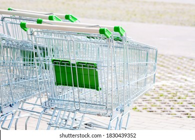 Multiple empty green shopping carts outside the grocery store, nobody. Lots of simple shop trolleys outdoors on the super sam, convenience store parking lot. Retail and consumerism abstract concept