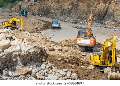 Multiple excavators operating in a river channel to repair erosion damage, moving rocks and soil for flood control and land stabilization.
