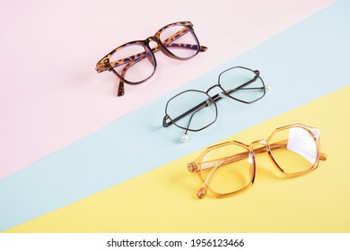multiple eyeglasses on a multicolored background of pastel colors, geometric background, pink yellow and light blue colors, trendy eyeglass frames copy space - Shutterstock ID 1956123466