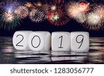 Multiple firework explosions against dark blue sky with calendar date and water reflections for 2019 New Years celebrations