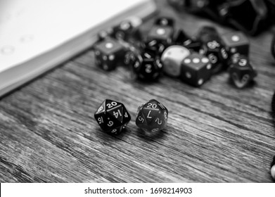 Multiple gaming dice on wooden table with 20 shown on a pair of d20