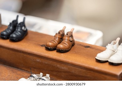 multiple handmade doll mini leather shoes displayed on wooden table