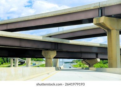 Multiple highway overpasses create unique architectural view under with vehicles traveling below.