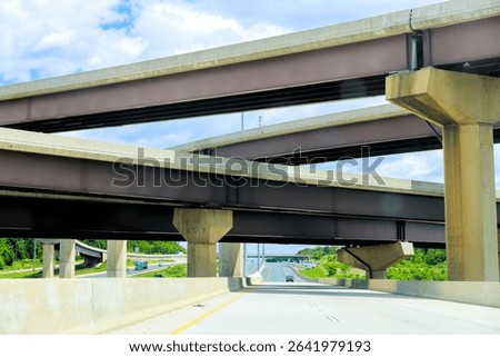 Multiple highway overpasses create unique architectural view under with vehicles traveling below.