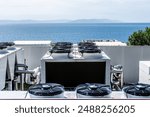 Multiple industrial air conditioning units on a building rooftop, equipped with fans and ventilation systems, overlooking a vast sea with distant islands. Perfect blend of technology and nature.