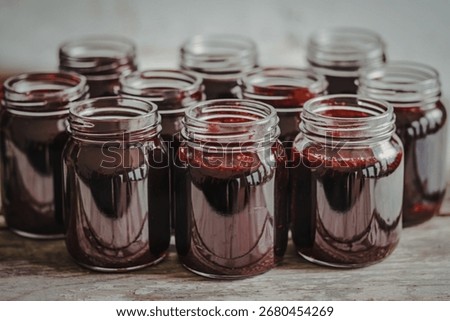 multiple jam jar bottles filled with a dark red jam