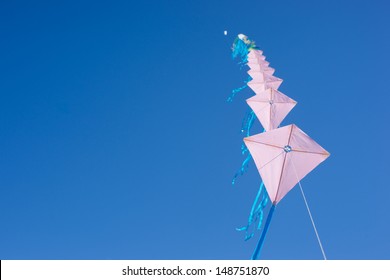 Multiple Kites On A Row Against A Blue Sky