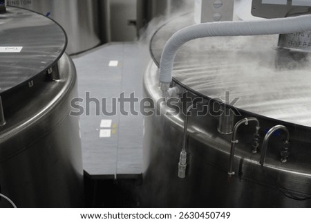 Multiple liquid nitrogen storage tanks with visible cold vapor and connected piping in a cryogenic storage facility.