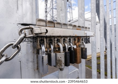 Multiple locks on a security gate. The removal of any one lock allows the gate to be opened.