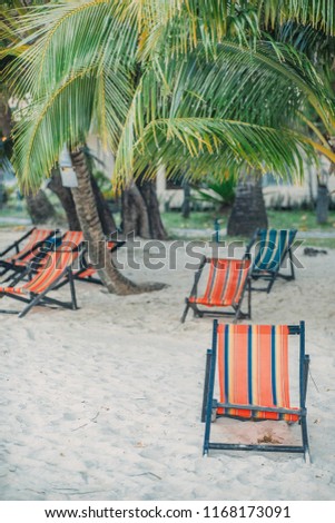Multiple lounge on the sandy beach chairs in the tree shadow under the palm. Sunset. Vacation postcard concept. Travel inspiration. Vintage effect. 