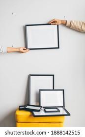 Multiple Many Black Picture Frames On White Wall. Woman Hanging A Frame On A Wall.