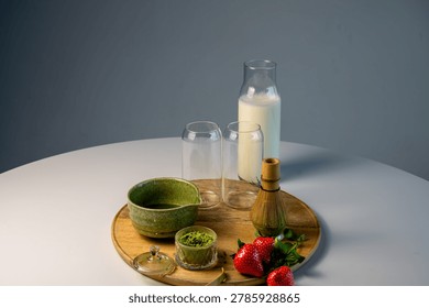 Multiple matcha beverages in different glasses arranged on wooden tray with ceramic bowl and strawberries. Cafe-style display with bamboo whisk and artisan presentation. Matcha drink menu, cafe beverage collection, artisan tea bar concept