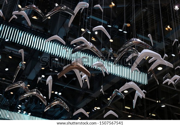 Multiple metal colored Citroen logos hanging from\
the roof in Geneva International Motor Show (GIMS), Geneva\
Switzerland March 2019. Group of white, silver and golden Citroen\
logos. Color image.