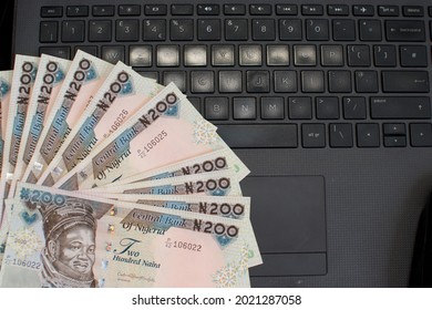 Multiple naira notes, cash or nigerian currency spread neatly on a laptop's key board
