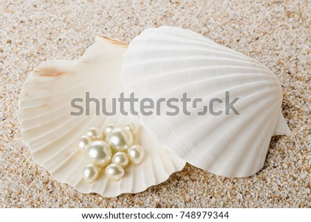 Multiple pearls in sea shell over sand background