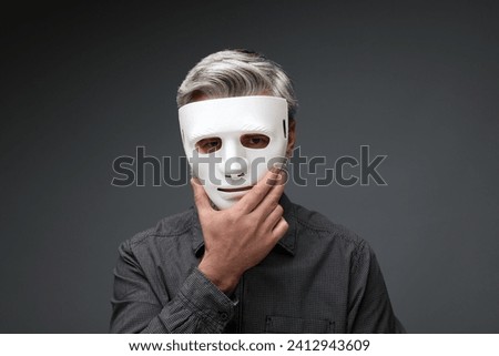 Multiple personality concept. Man in mask on dark grey background