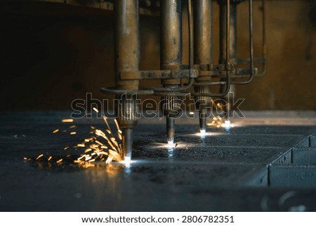 Multiple plasma cutting torches simultaneously cutting a metal sheet in a factory