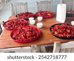 Multiple platters filled with bright red crawfish arranged on a rustic wooden table, along with small bowls and a paper towel roll, capturing the setup of a classic Louisiana crawfish boil. 