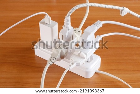 Multiple plugs on the table electrical outlet is dangerous overload, close-up