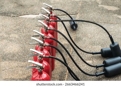 Multiple red fire extinguishers connected on a concrete surface, showcasing essential safety equipment for emergency response and fire prevention measures.