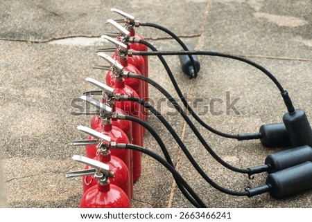 Multiple red fire extinguishers connected on a concrete surface, showcasing essential safety equipment for emergency response and fire prevention measures.