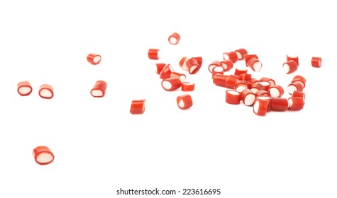 Multiple red and white candy sweets spilled over the white surface, composition isolated over the white background