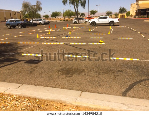 Multiple remote control miniature\
cars racing around a course laid out on an asphalt parking\
lot
