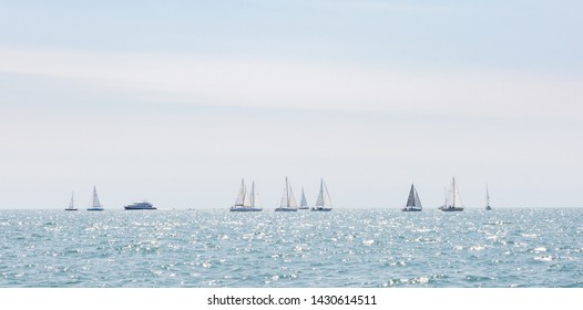 Multiple Sailboats Sailing On The Ocean On A Bright Sunny Day