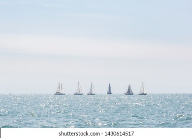 Multiple Sailboats Sailing On The Ocean On A Bright Sunny Day