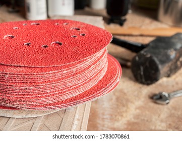 Multiple Sanding Pads For Grinder Or Drill On Workshop Table. Perspective View. Soft Background With Sawdust On Table, Mallet And Wrench. DIY Or Carpentry Concept.