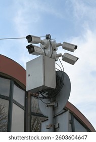 Multiple security cameras are positioned on a pole, observing a modern building