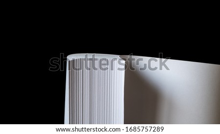 Multiple sheets of curved A4 paper (ream) on black background.   Simple, isolated object ideal for illustrating various concepts with space for headings and other texts. Selective focus  (shallow DOF)