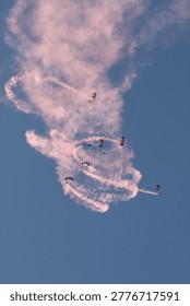 Multiple skydivers create intricate red smoke patterns during a dynamic aerial display.