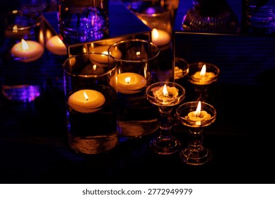 Multiple small white candles floating in water-filled glass vases create a warm and romantic atmosphere.