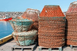 Multiple Stacks Of Industrial Crab Traps Or Pots For Commercial Fishing. The Round Nets Have Metal Frames With Orange Fishing Rope Enclosing The Trap. The Center Contains A White Plastic Food Holder. 